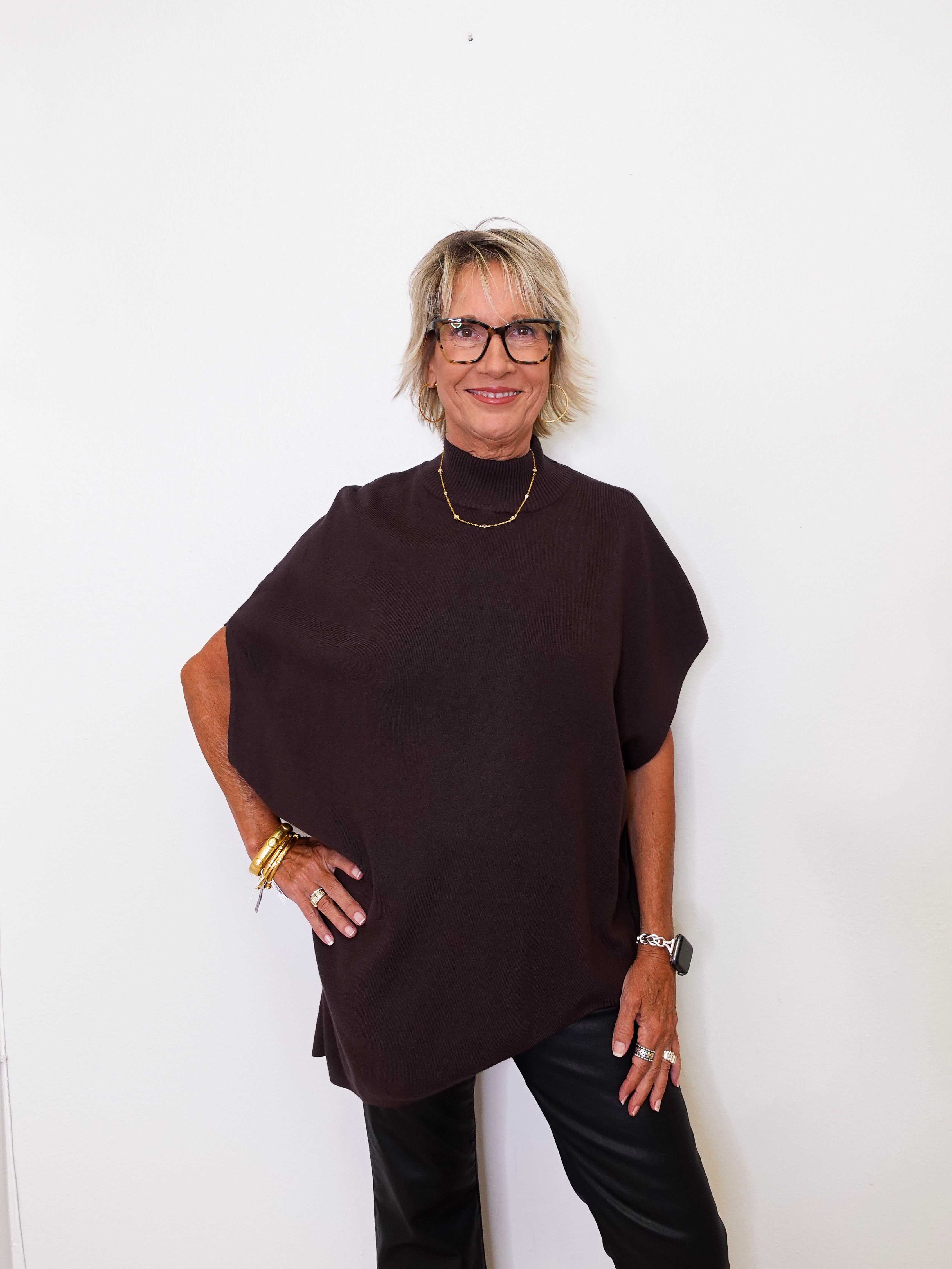 Woman wearing a dark brown poncho against a white background