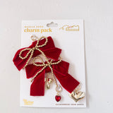 Red bow charm with gold accents and a heart detail on a white card packaging.