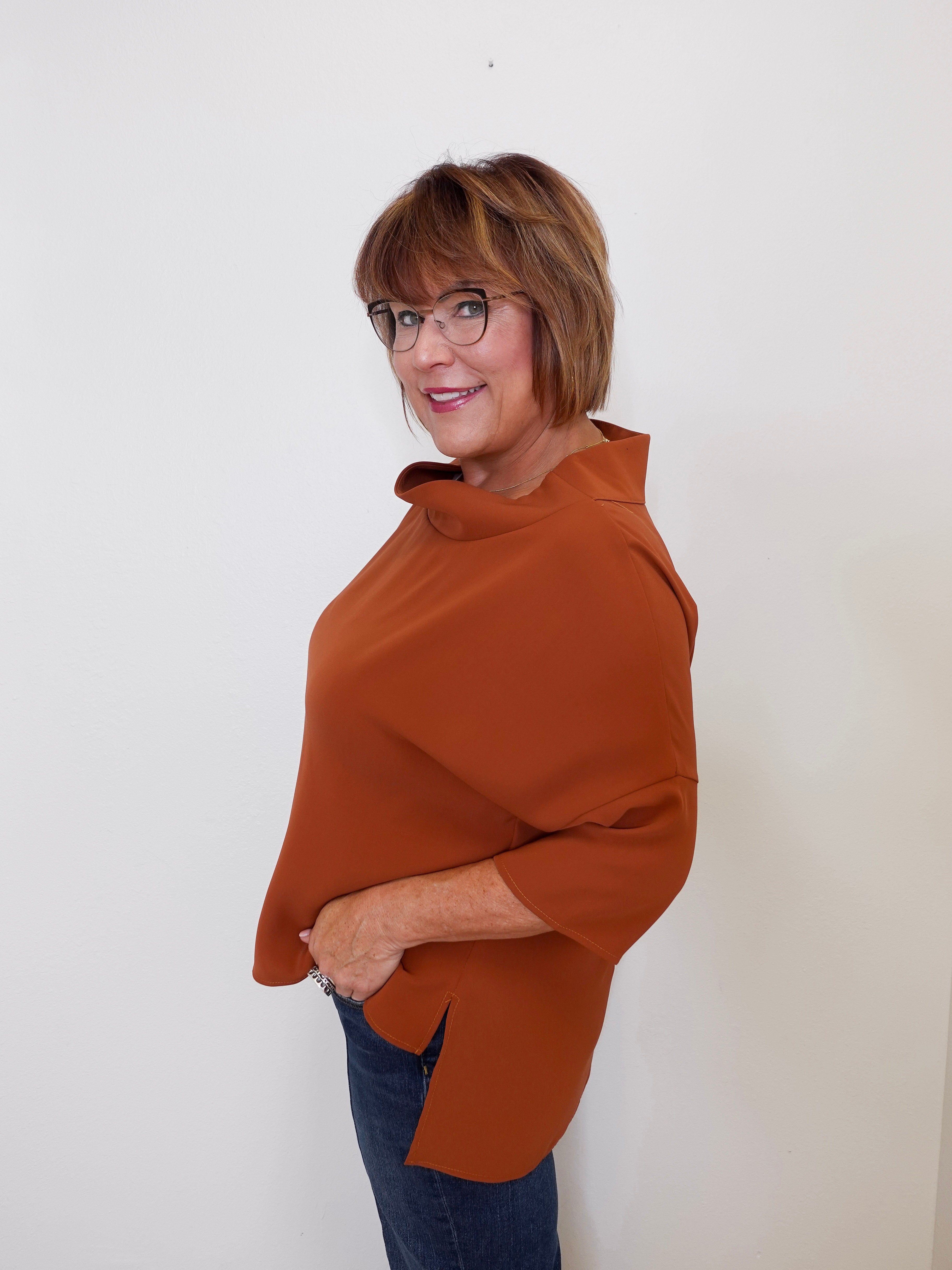 Woman wearing a brown poncho against a white background