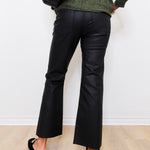 Person wearing black wide-leg pants and a green sweater against a white wall.