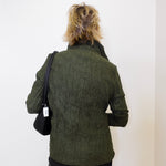 Person wearing a green textured jacket with a black bag on a white background