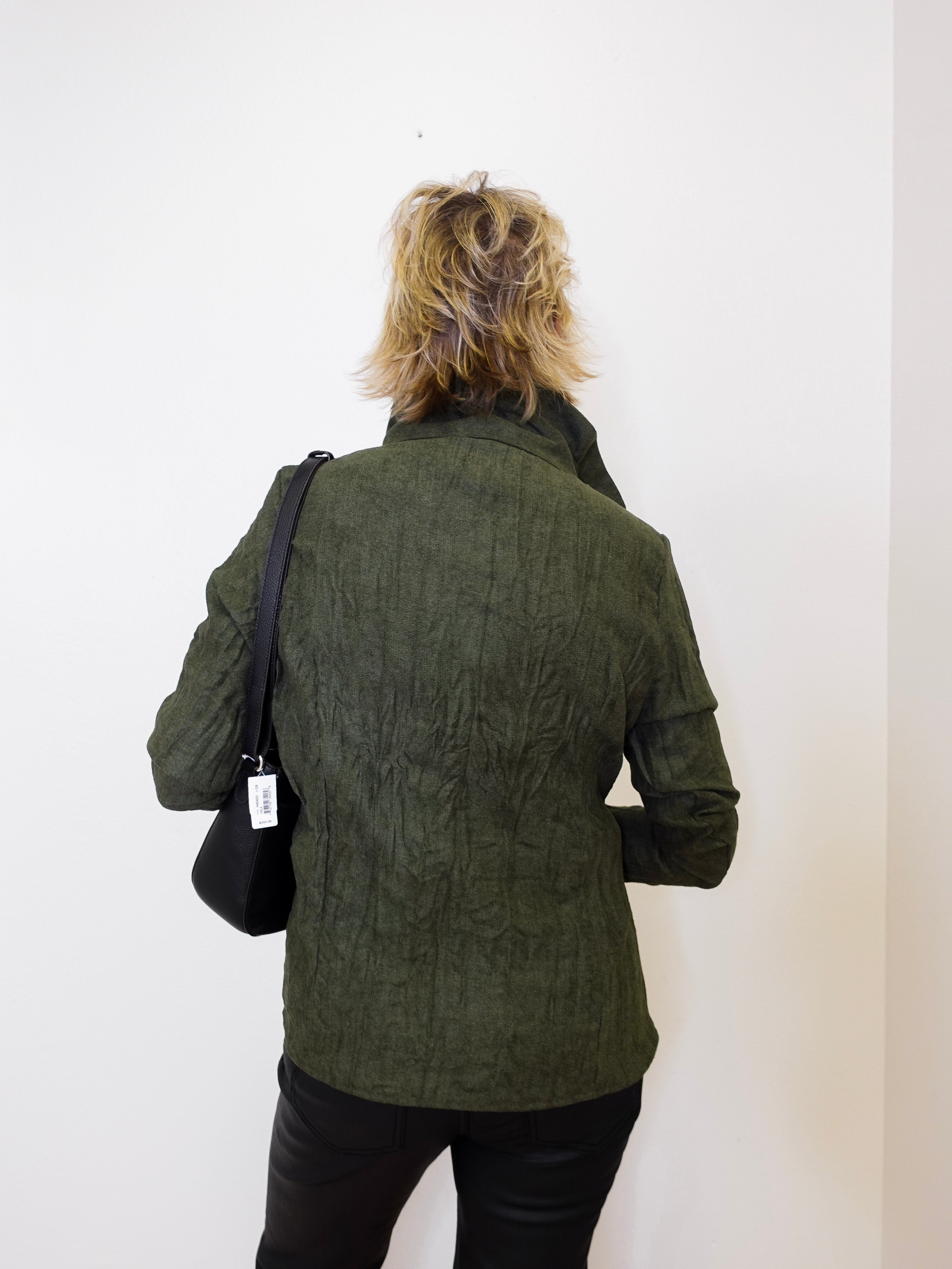 Person wearing a green textured jacket with a black bag on a white background