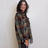 Woman wearing a plaid shawl against a white wall