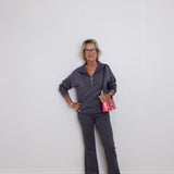 Woman in gray outfit standing against a white wall