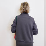 Person wearing a gray tracksuit against a white wall
