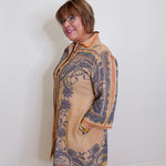 Woman wearing a patterned coat against a white wall