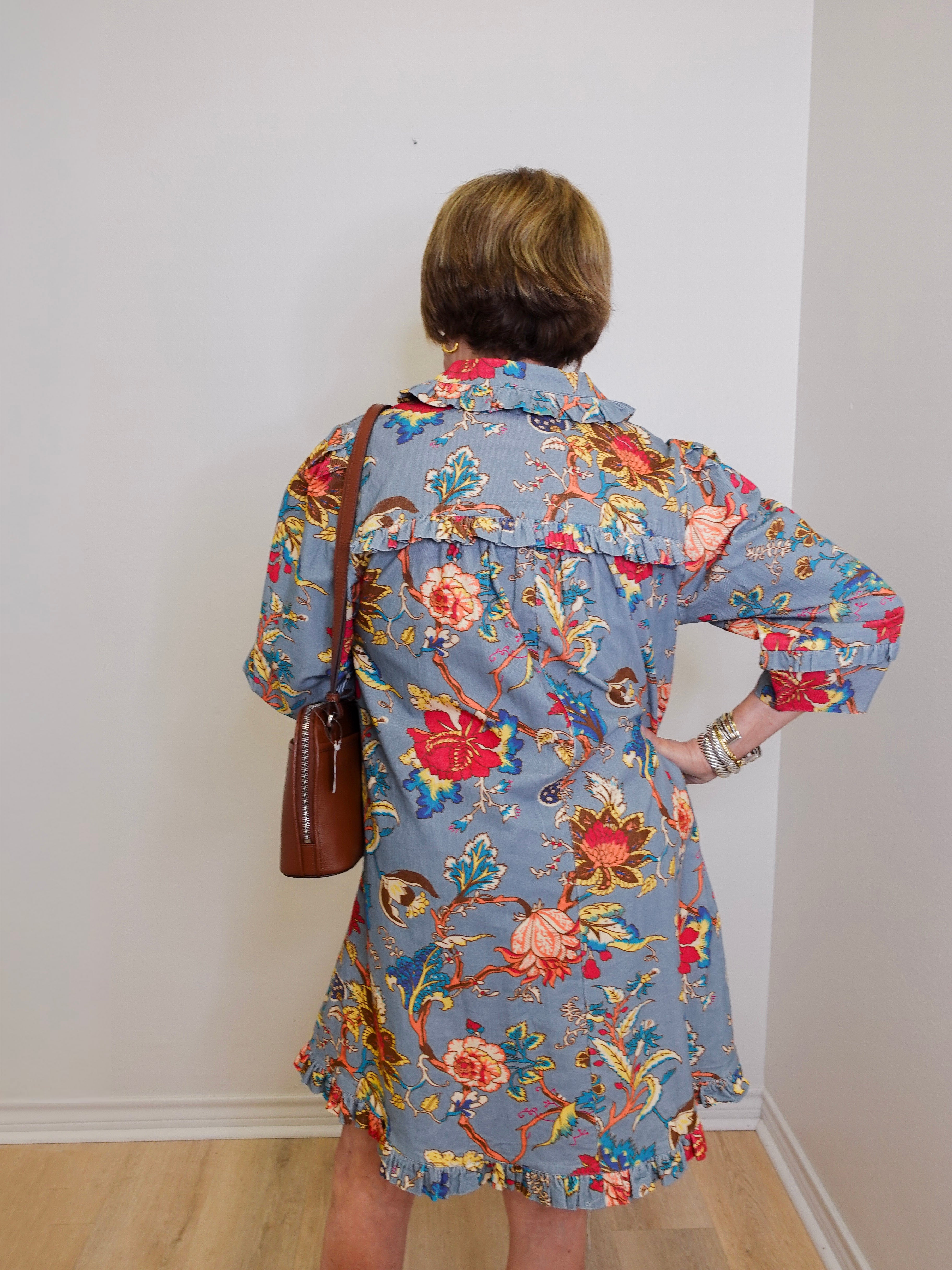 Person wearing a floral dress with a plain white wall background