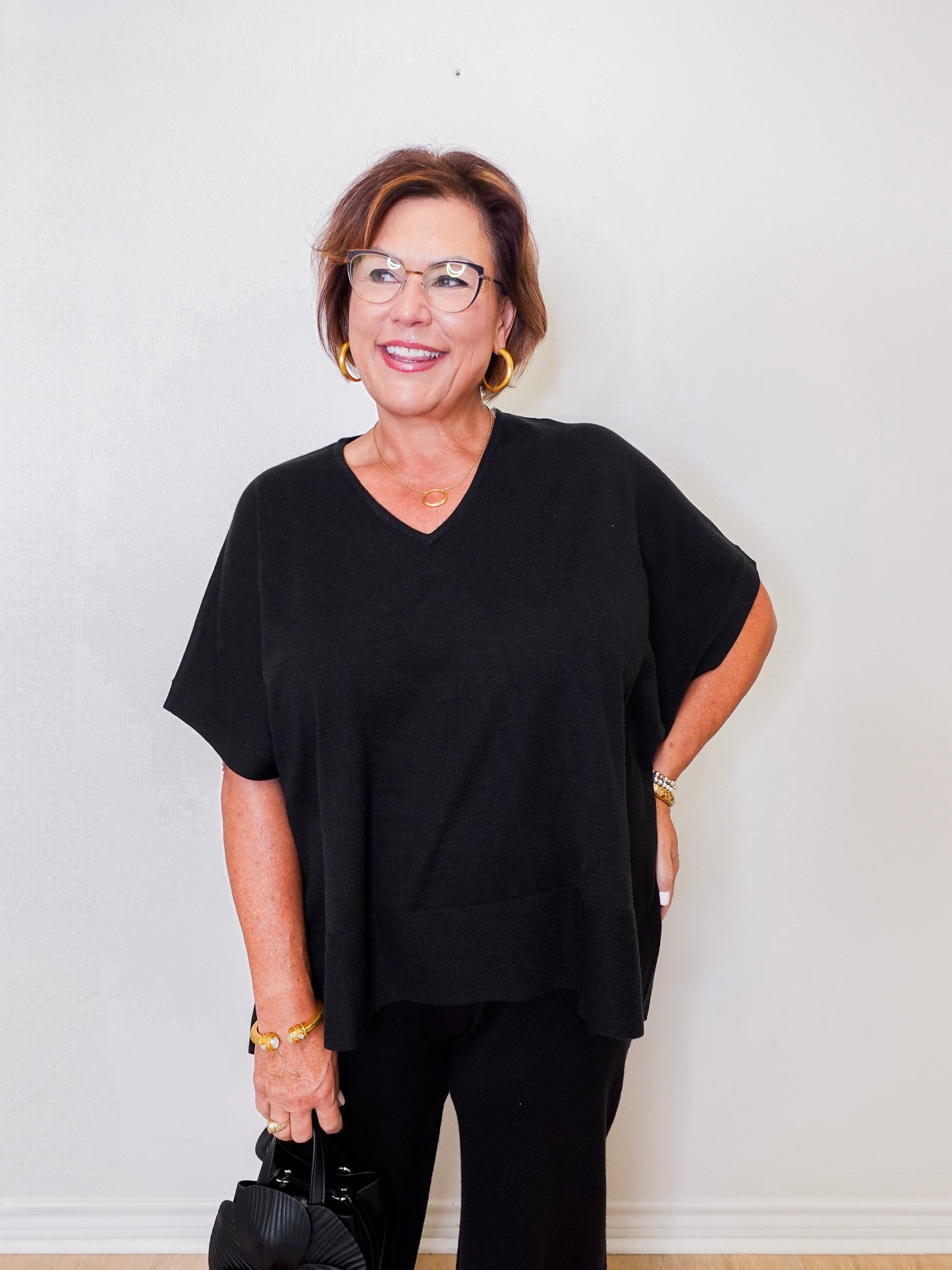 Woman wearing a black outfit with glasses against a white background