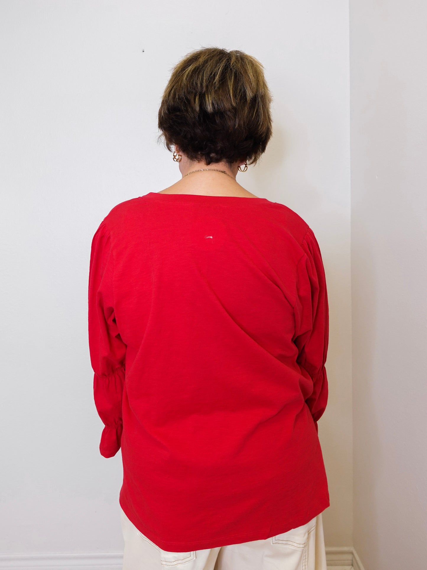 Person wearing a red shirt standing against a white wall