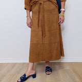 Person wearing a brown skirt with a white wall background