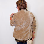 Person wearing a beige jacket against a white wall