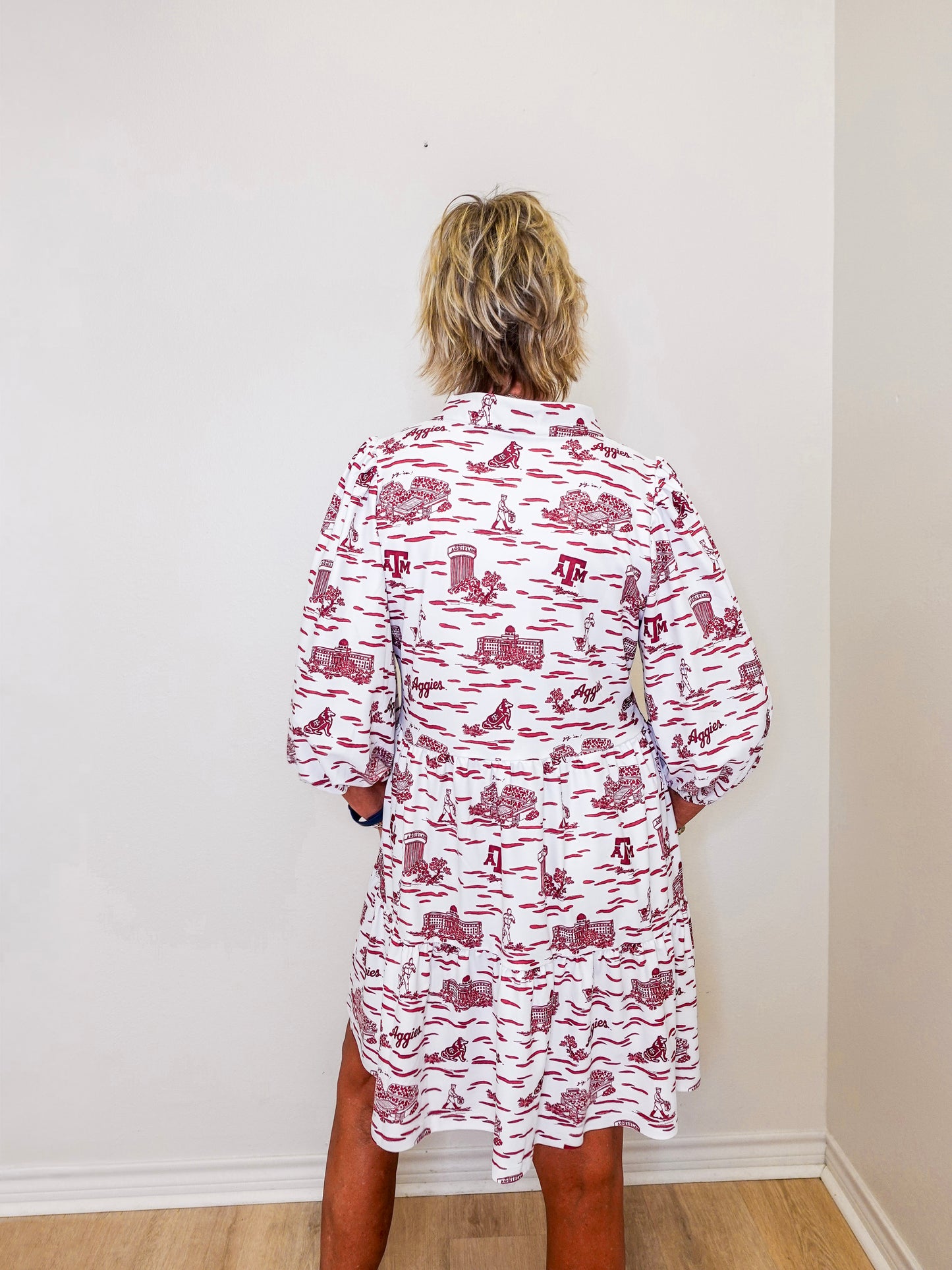 Person wearing a red and white patterned dress against a plain wall.