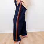 Person wearing dark blue jeans with a striped pattern on a light wooden floor.