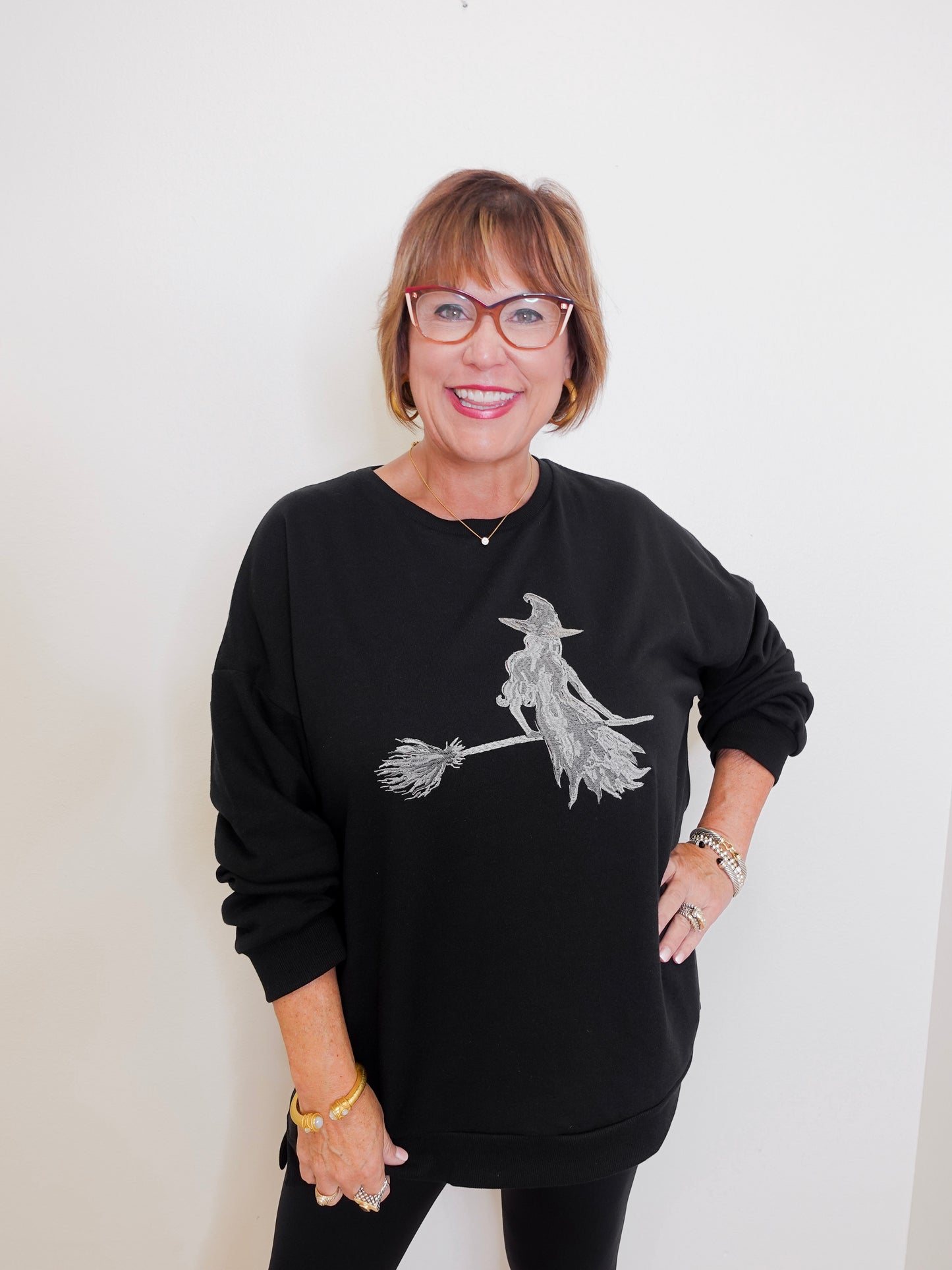 Woman wearing a black sweatshirt with a witch design on a white background