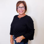 Woman wearing a black top and blue jeans with a white background