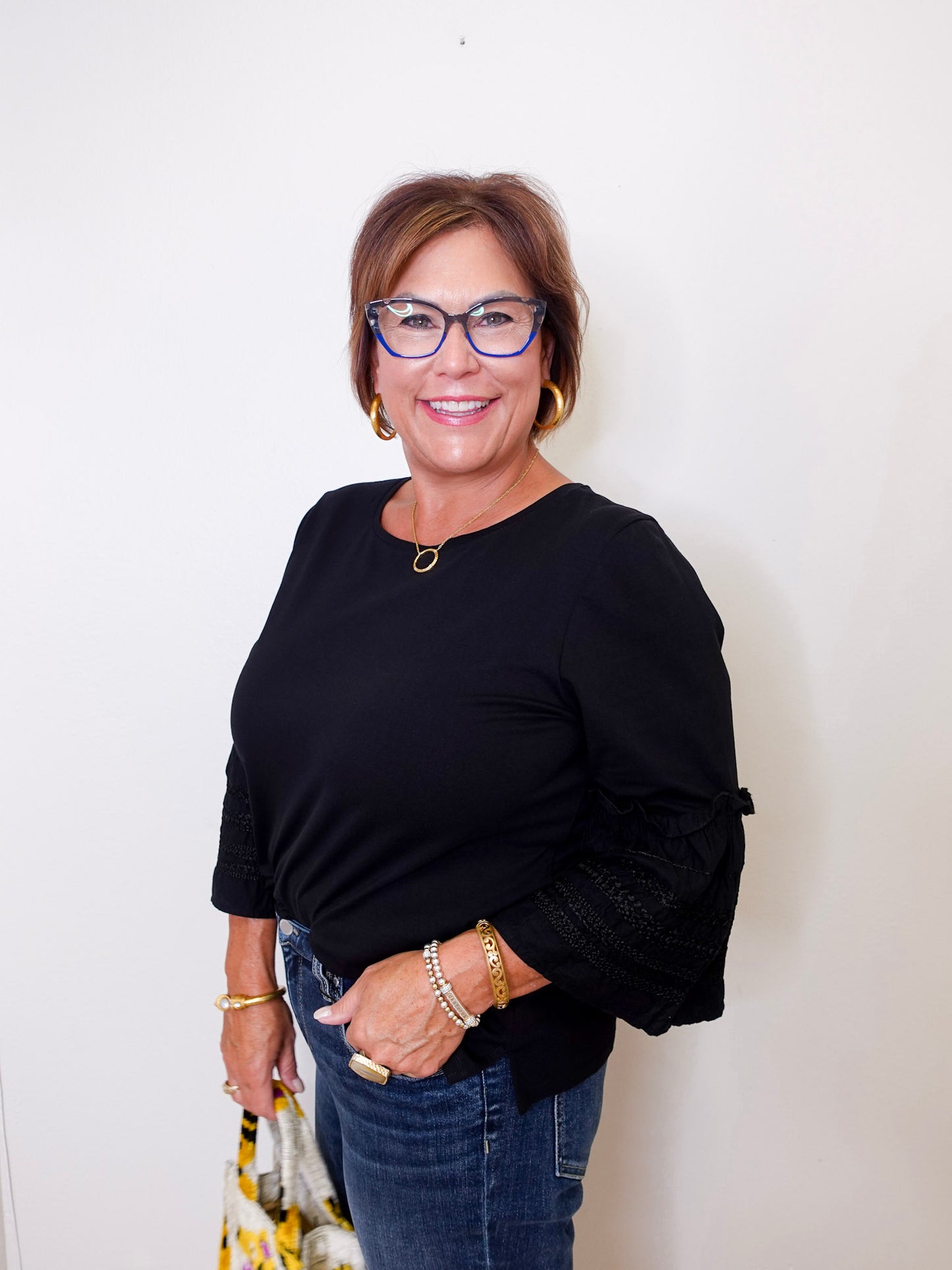 Woman wearing a black top and blue jeans with a white background