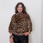 Woman wearing a leopard print sweater against a white wall