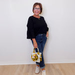 Woman holding a patterned handbag against a white wall