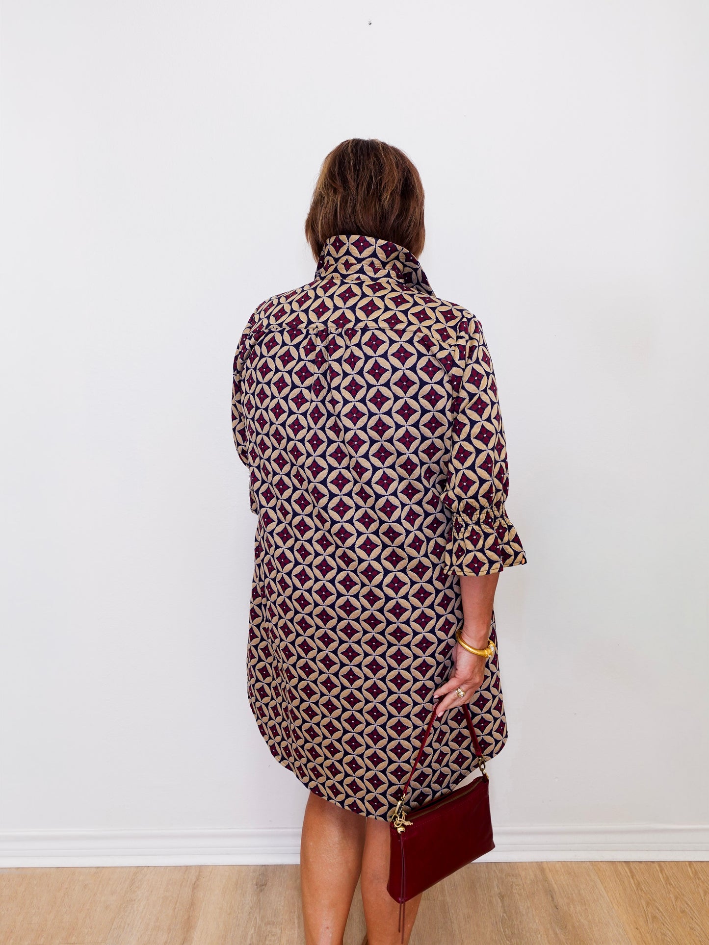 Person wearing a patterned dress against a white wall