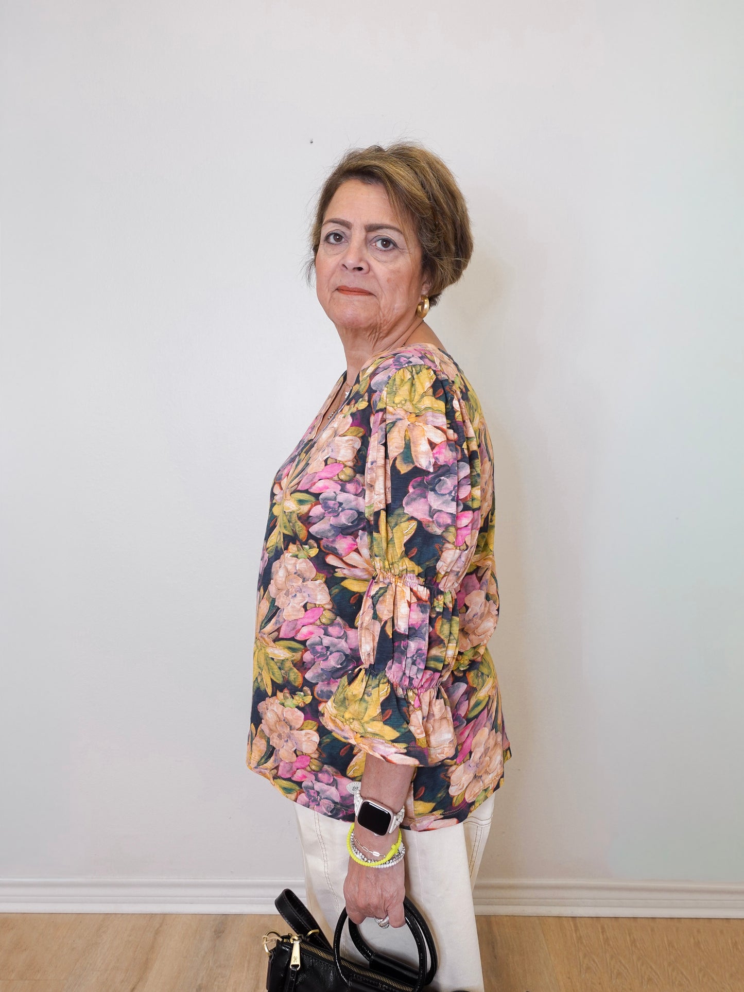 Woman wearing a floral blouse against a white wall