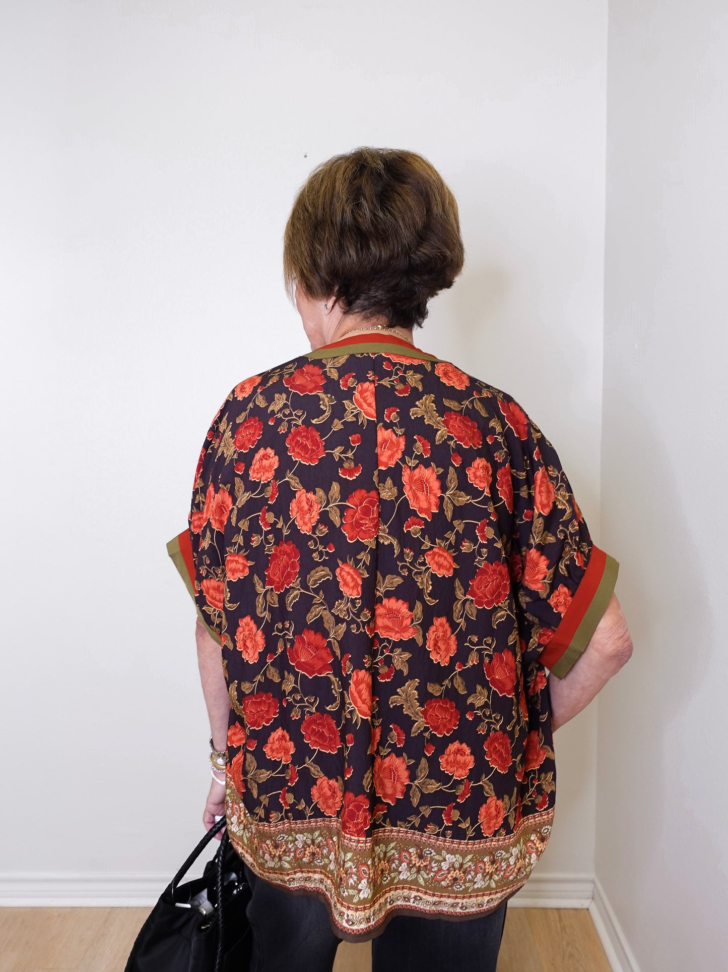a women wearing a black floral short sleeve top in front of a white background