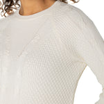 Close-up of a person wearing a textured white sweater on a plain background