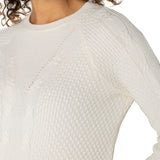 Close-up of a person wearing a textured white sweater on a plain background