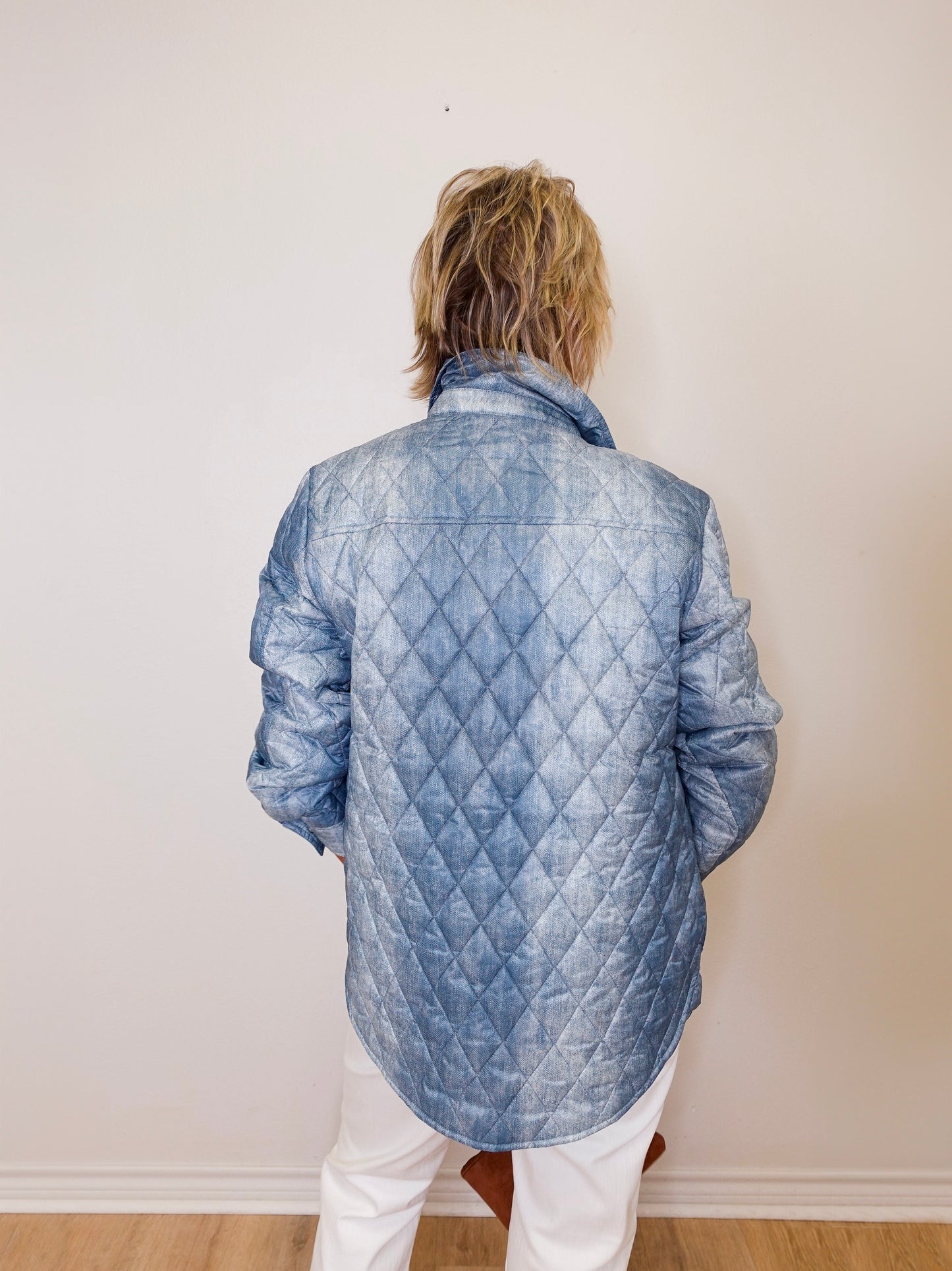 Person wearing a blue quilted jacket against a plain background