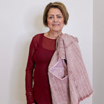 Woman wearing a red top and pink scarf against a white background