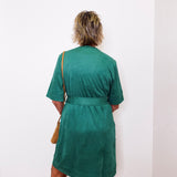 Person wearing a green dress against a white wall