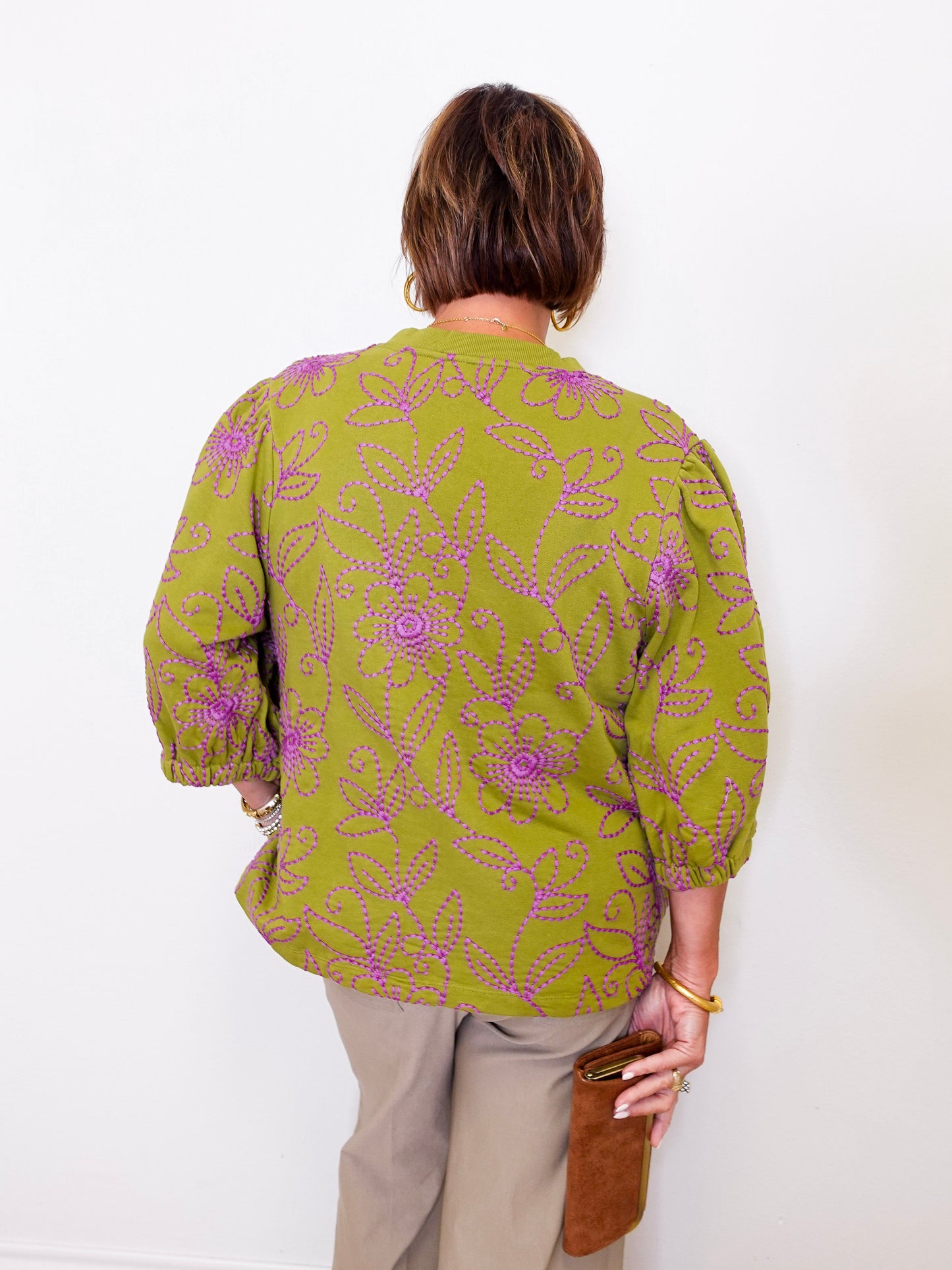 Person wearing a green patterned blouse against a white background