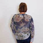 Person wearing a floral-patterned long-sleeve shirt against a white background