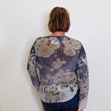 Person wearing a floral-patterned long-sleeve shirt against a white background