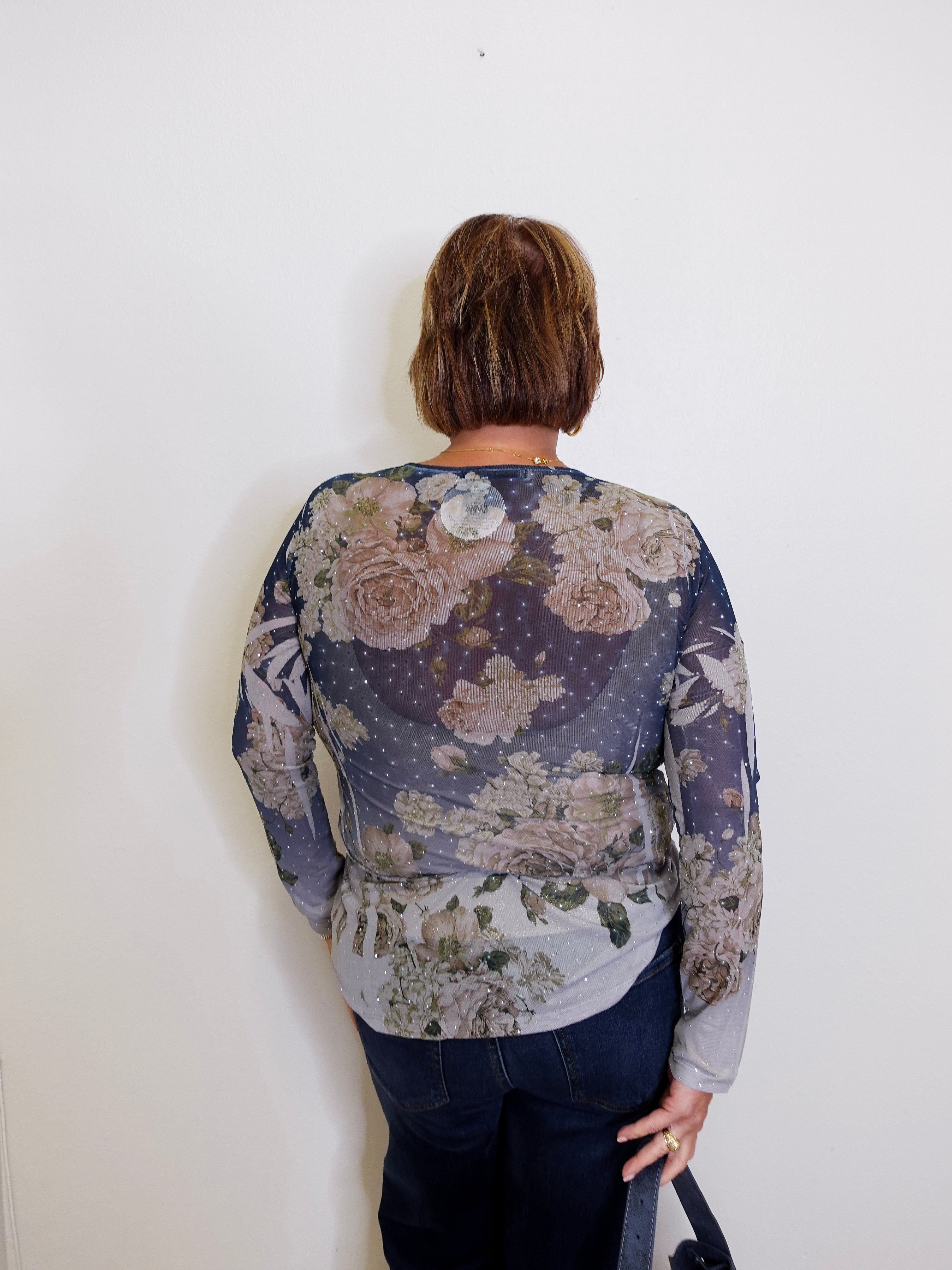 Person wearing a floral-patterned long-sleeve shirt against a white background