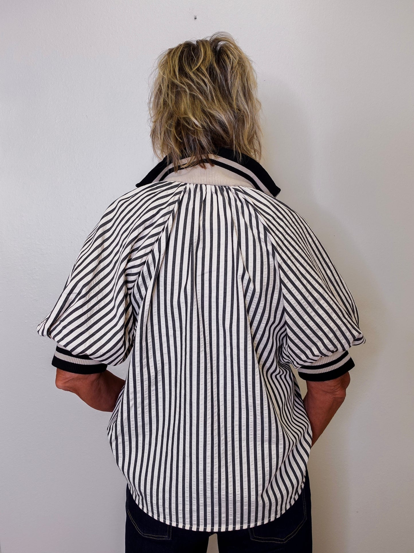 Person wearing a black and white striped shirt against a plain background
