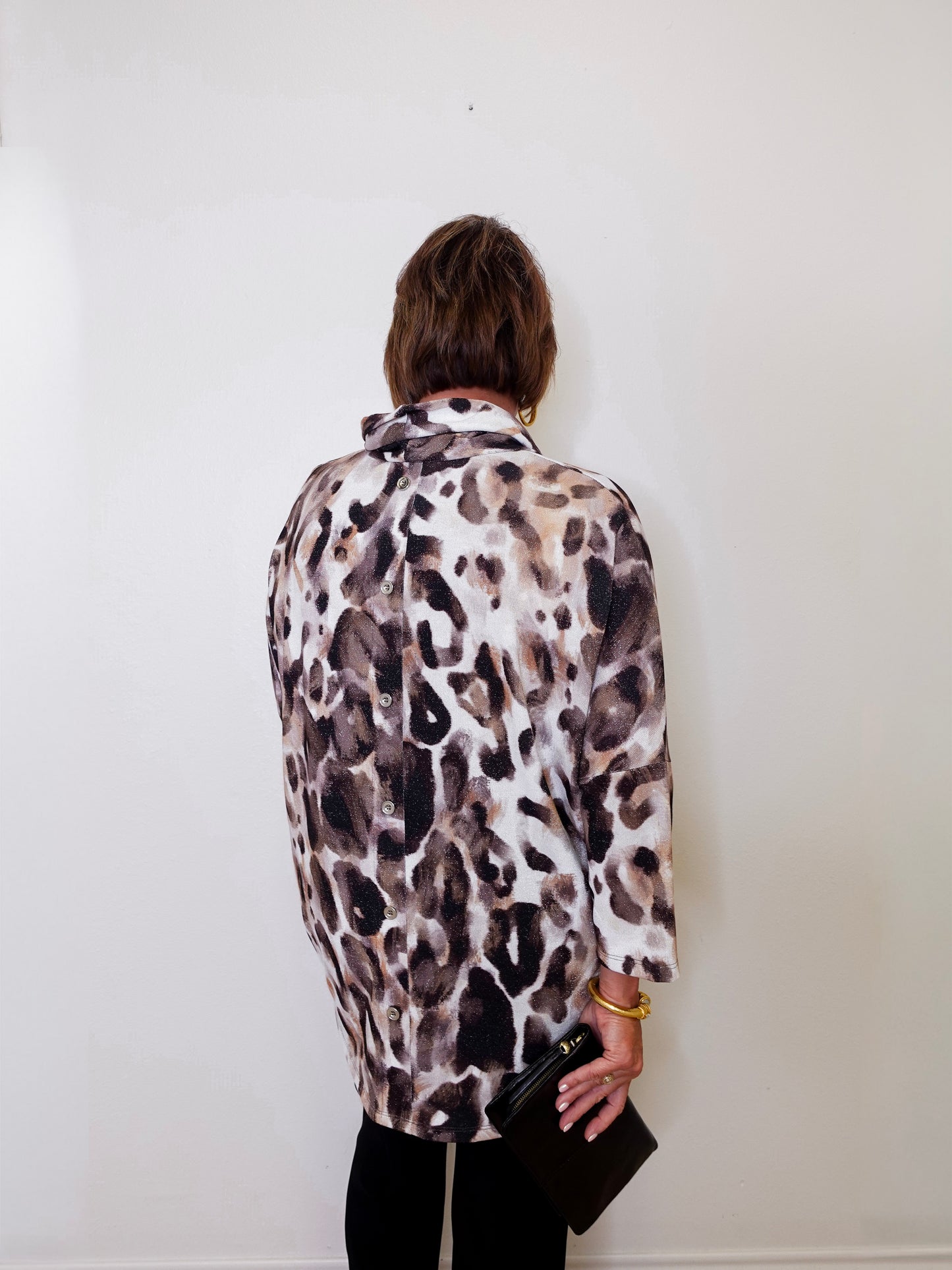 A woman wearing a Joseph ribkoff cowl neck leopard print pullover sweater in front of a white wall.