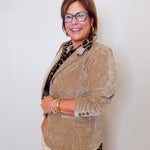 Woman wearing a beige blazer and glasses against a white background