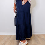 Person wearing a navy tiered skirt with white sneakers against a plain background