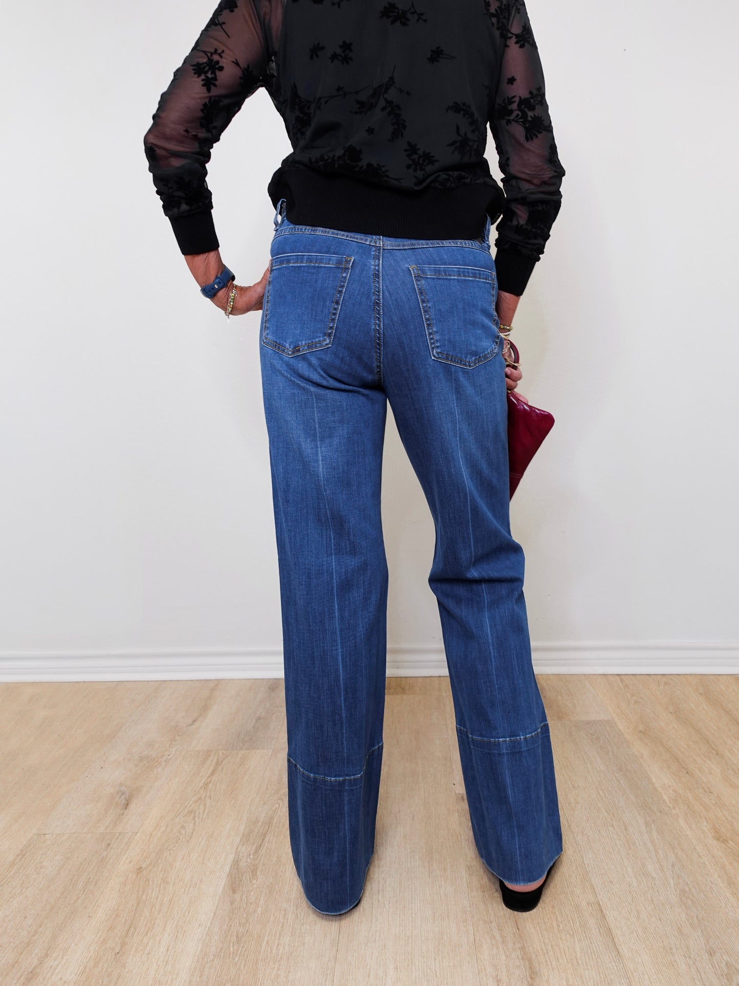 A woman modeling high rise wide leg jeans in front of a white wall.
