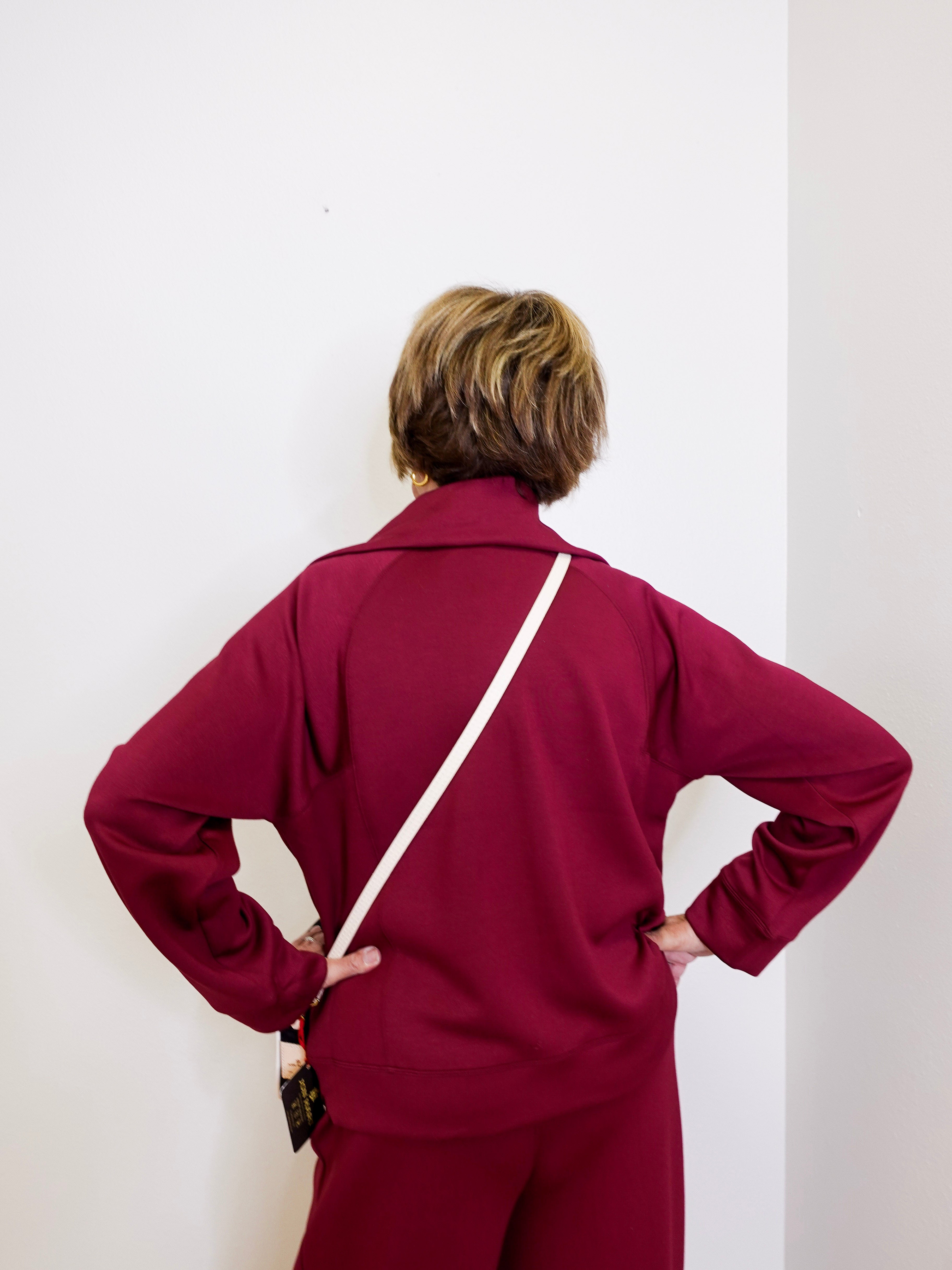Person wearing a burgundy tracksuit against a white background