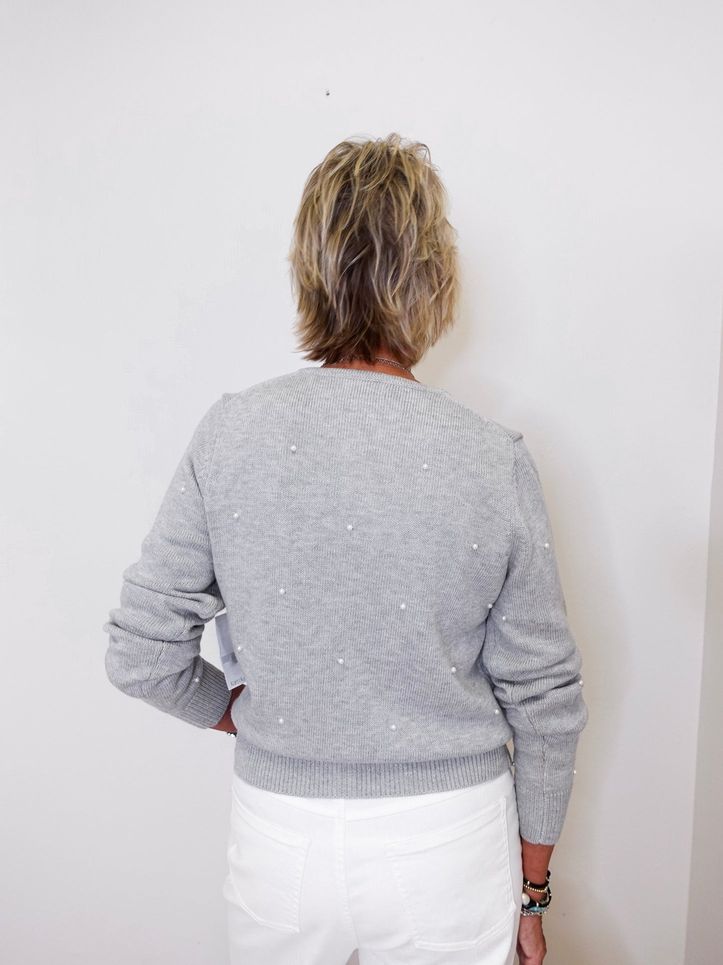 Person wearing a gray sweater with white polka dots against a white background