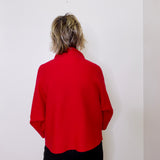 Person wearing a red shirt against a white wall