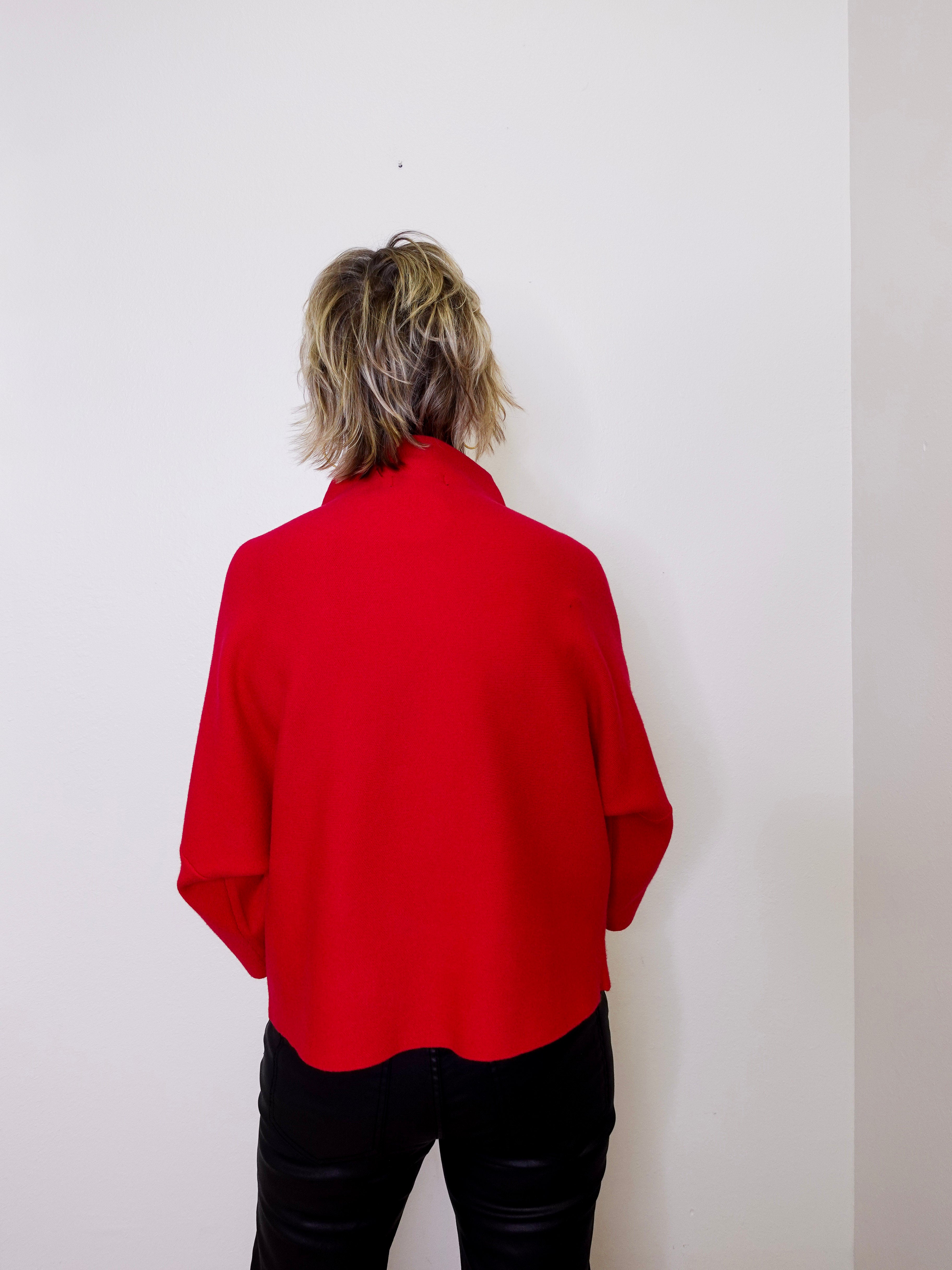 Person wearing a red shirt against a white wall
