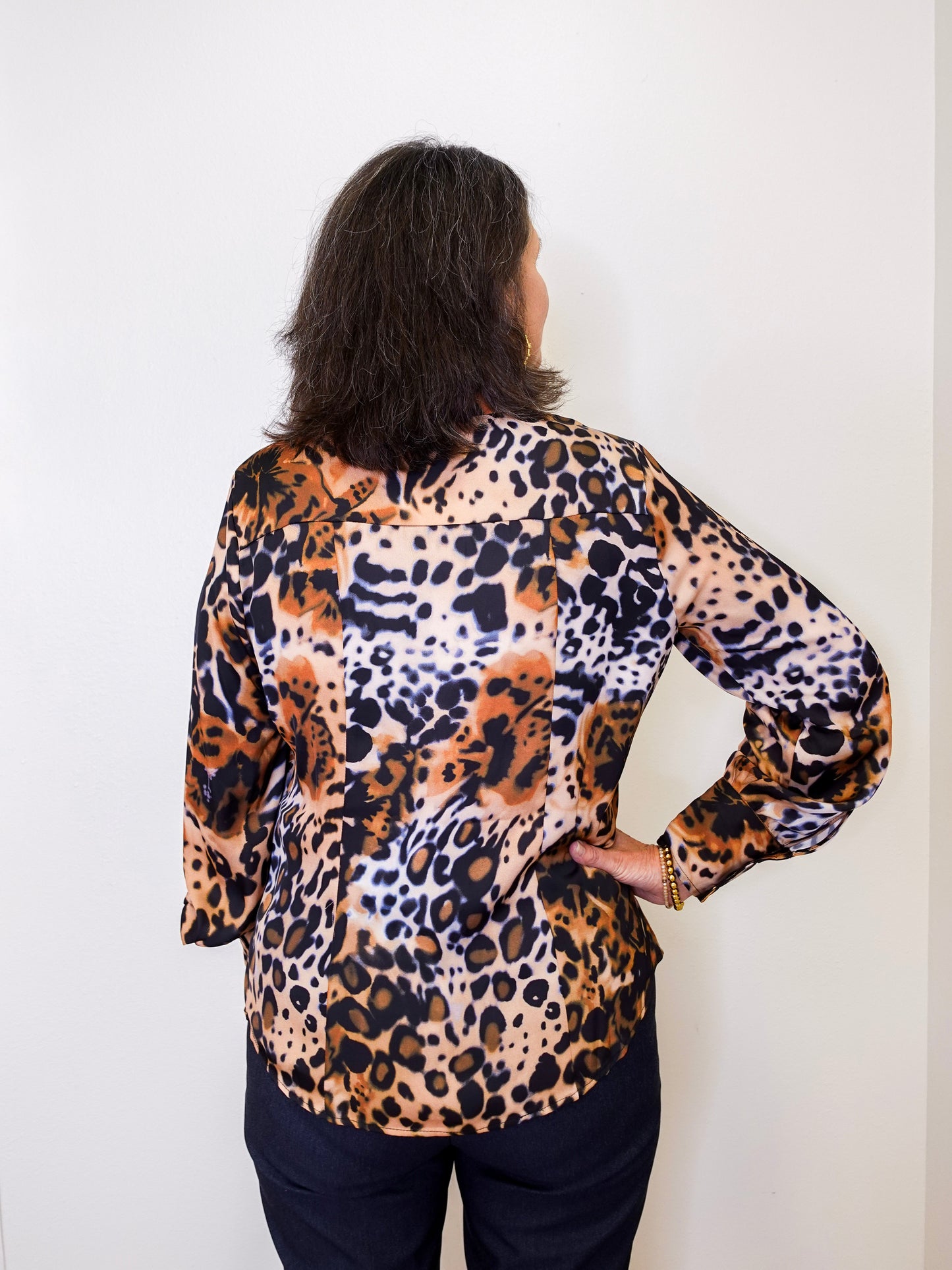 Person wearing a leopard print top against a white background