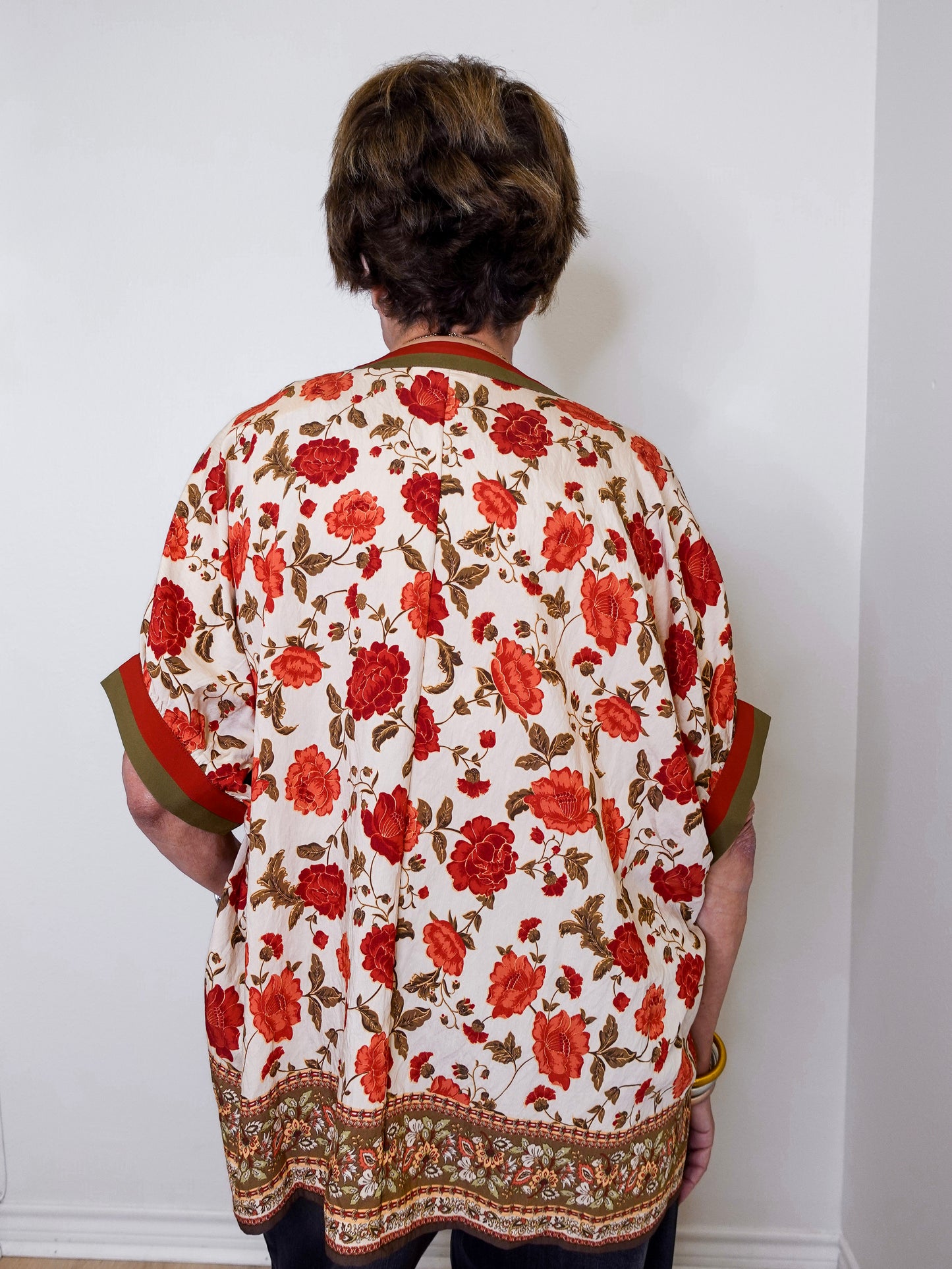 women wearing a floral print blouse against a white wall.