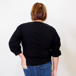 Person wearing a black top and blue jeans against a white background