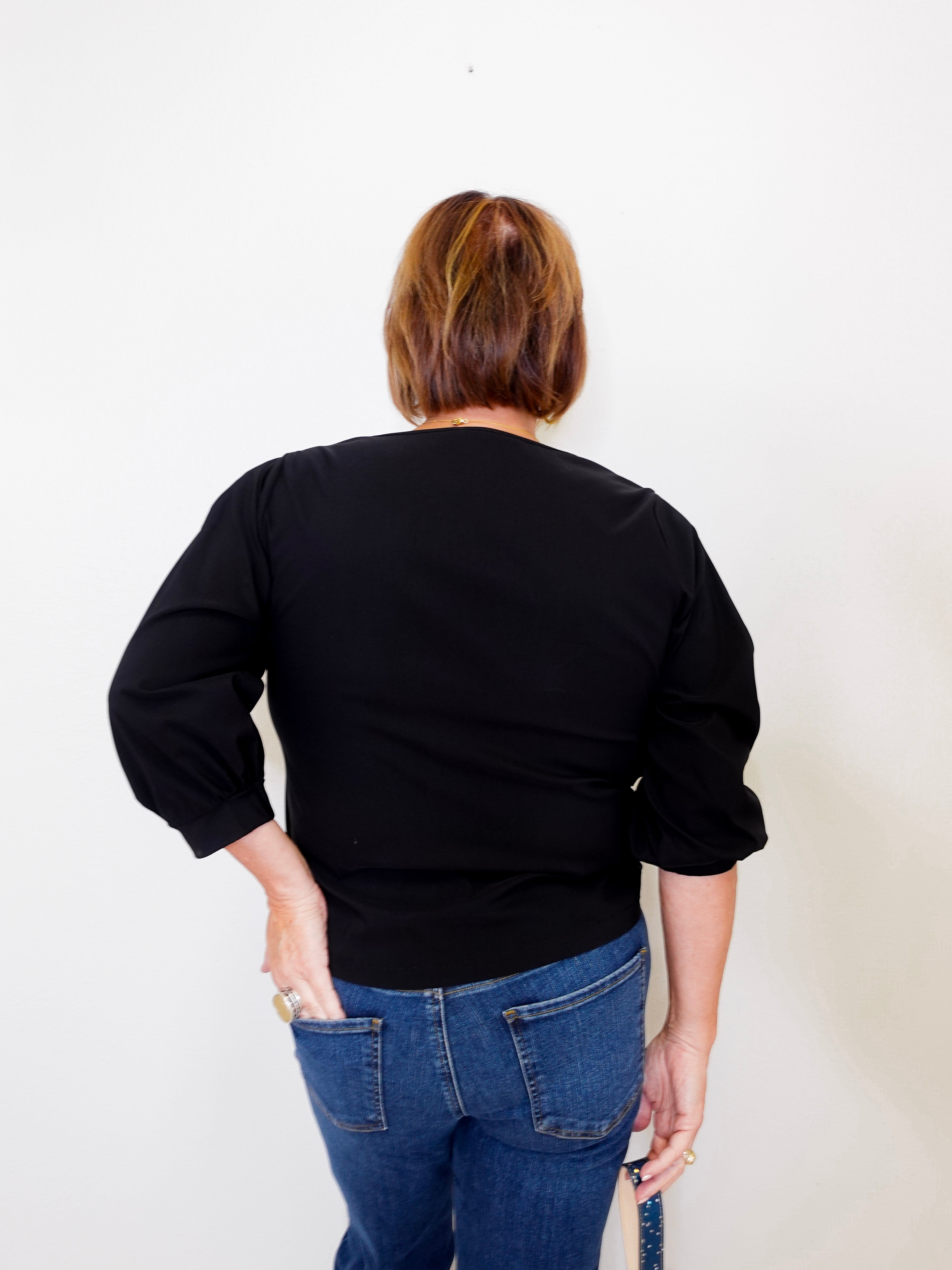 Person wearing a black top and blue jeans against a white background