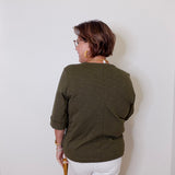 Person wearing a green shirt and white shorts against a plain wall