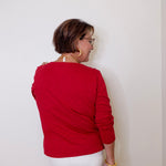 Person wearing a red top and white shorts against a plain background