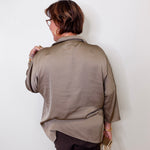 Person wearing a beige top against a white wall